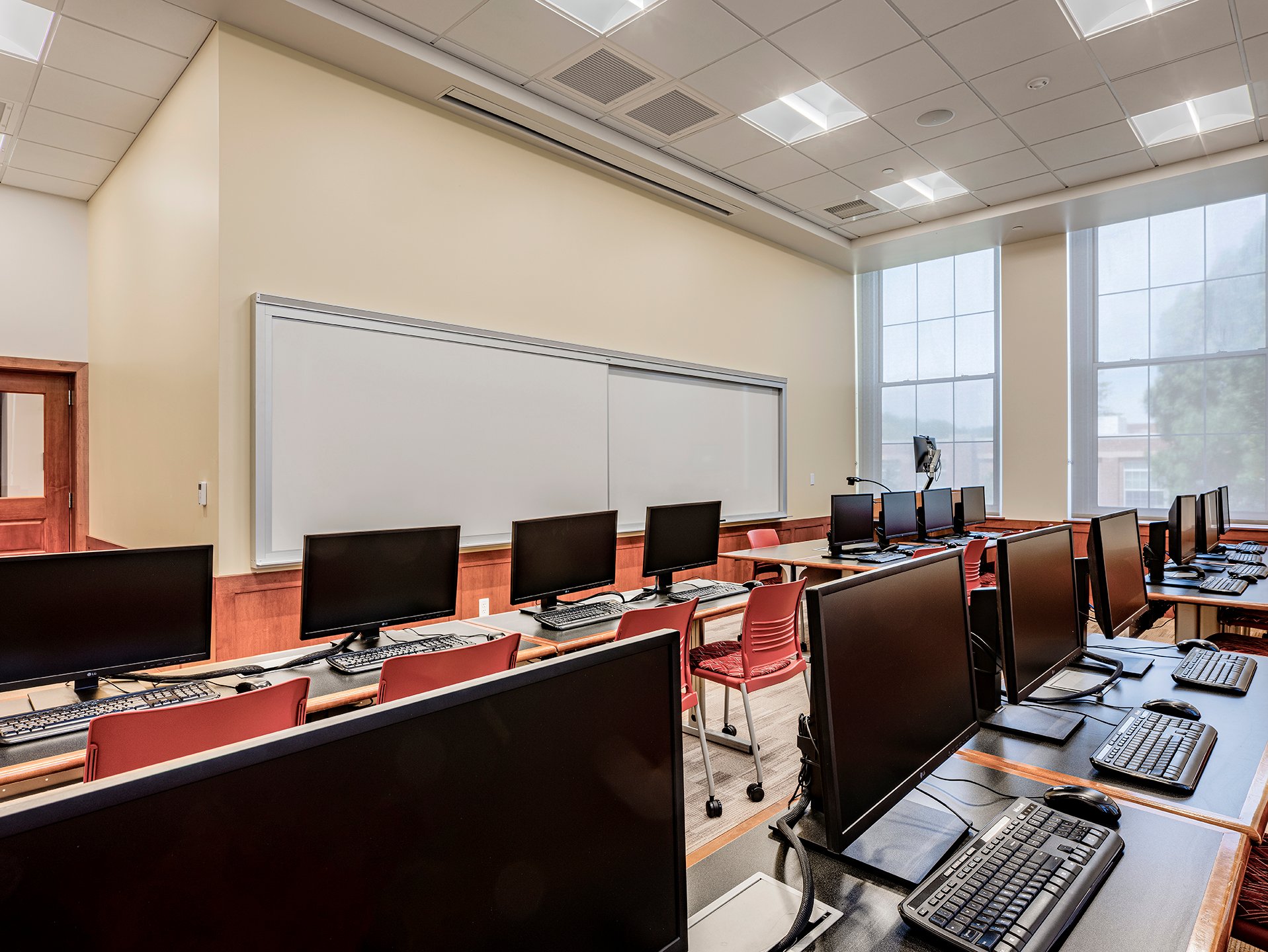 Interior, Percival Hall classroom at Fitchburg State University, rows of desks with computers, chairs, lectern and computer, whiteboard, etc. 