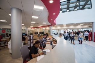 Student Central One Stop at Bunker Hill Community College, student services center area with kiosks, staff and students in the space