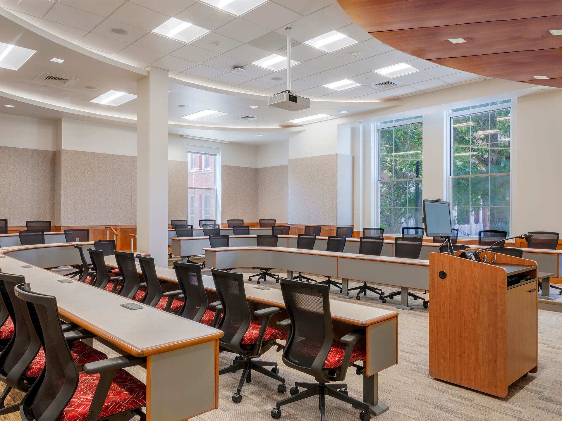 Interior, Percival Hall classroom at Fitchburg State University, continuous desks in a U-shape, chairs, lectern, computer, etc.