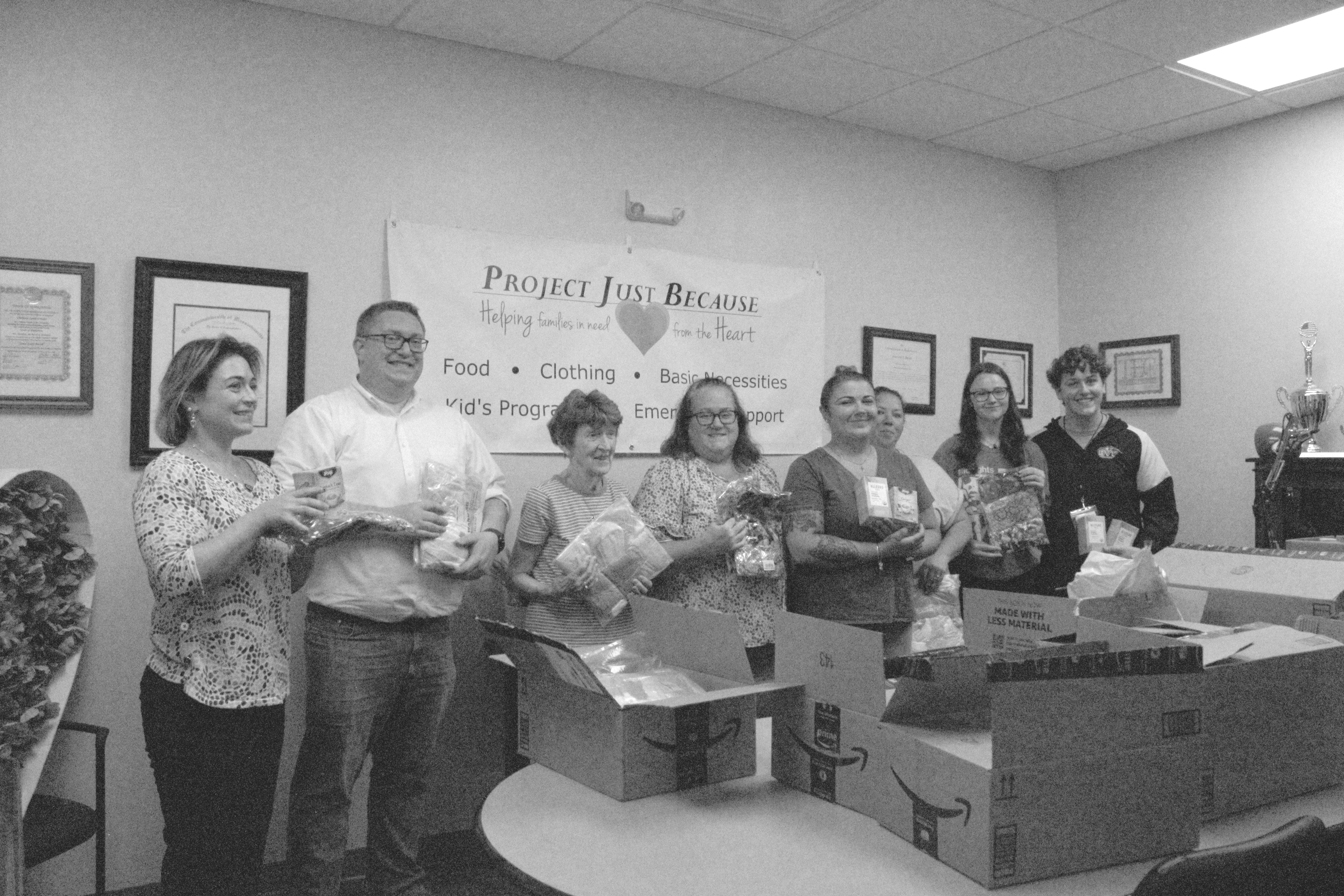 Members from Project Just Because and Matz Collaborative Architects hold up and stand in front of the donated items